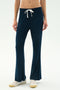 A person wears the SPLITS59 Blaire Rib Pant in Indigo—navy blue drawstring lounge pants crafted from soft modal with spandex—paired with white sneakers, standing against a plain light background.
