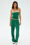 A woman models the SPLITS59 Monah Rigor Tank - Arugula/White against a plain backdrop. Her green top and matching pants, both crafted from nylon, are paired with white shoes.