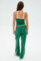 Someone with long hair is wearing the comfortable Arugula/White Monah Rigor Tank by SPLITS59, paired with green track pants featuring white stripes, standing facing away.