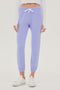 Front view of woman with straight dark brown hair wearing light purple sweatpant jogger with white drawstring and white cropped turtleneck long sleeve paired with white shoes 