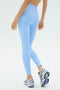 Model shown from the back wearing SPLITS59's Sprint High Waist Rigor 7/8 Leggings in Skylight with gray athletic sneakers against a plain light background.