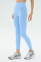 A person wearing SPLITS59 Sprint High Waist Rigor 7/8 leggings in Skylight and white running shoes stands against a plain light background.