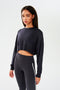 A woman wearing a SPLITS59 Noah Fleece Crop Sweatshirt in Graphite and athletic leggings.