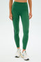 A person is seen in SPLITS59's Layla Airweight High Waist 7/8 leggings in Arugula/Indigo paired with white sneakers against a plain background.