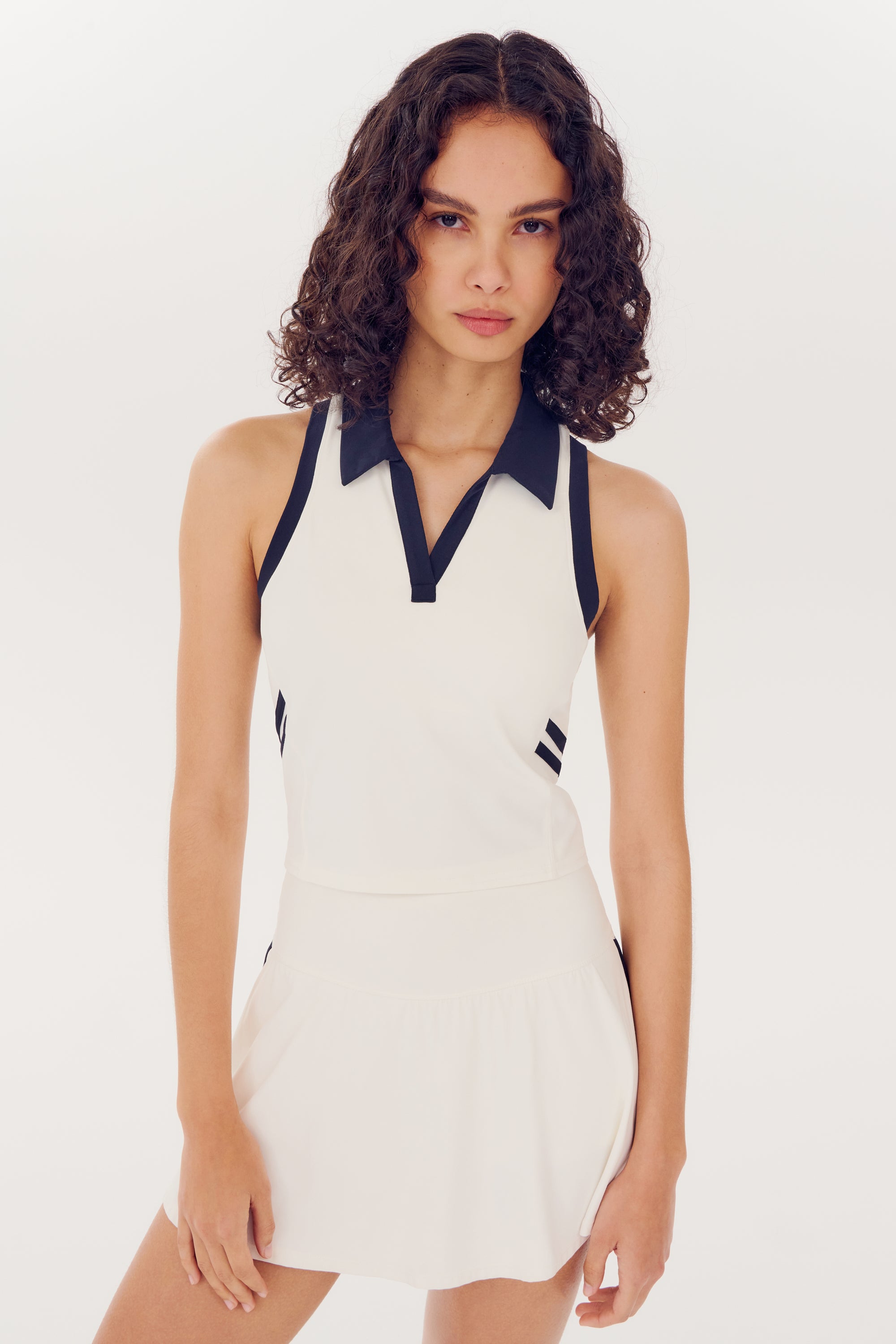 Woman modeling a SPLITS59 Austin Airweight Crop Polo in White/Indigo with black details made of nylon and spandex fabric.