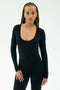 A woman with long braided hair wears the SPLITS59 Chloe Airweight Jumpsuit in black, standing against a plain light background.