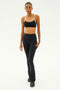 Dressed in the SPLITS59 Loren Seamless Bra in Black/White, paired with chafe-free leggings and black sneakers, a person stands poised in a studio, ready for intense gym workouts.