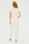 A person with curly hair, in a white t-shirt, Andie Oversized Fleece Sweatpant by SPLITS59, and sneakers, stands facing away against a plain backdrop. Ideal for cool weather workouts, this outfit showcases MADE IN LOS ANGELES craftsmanship.