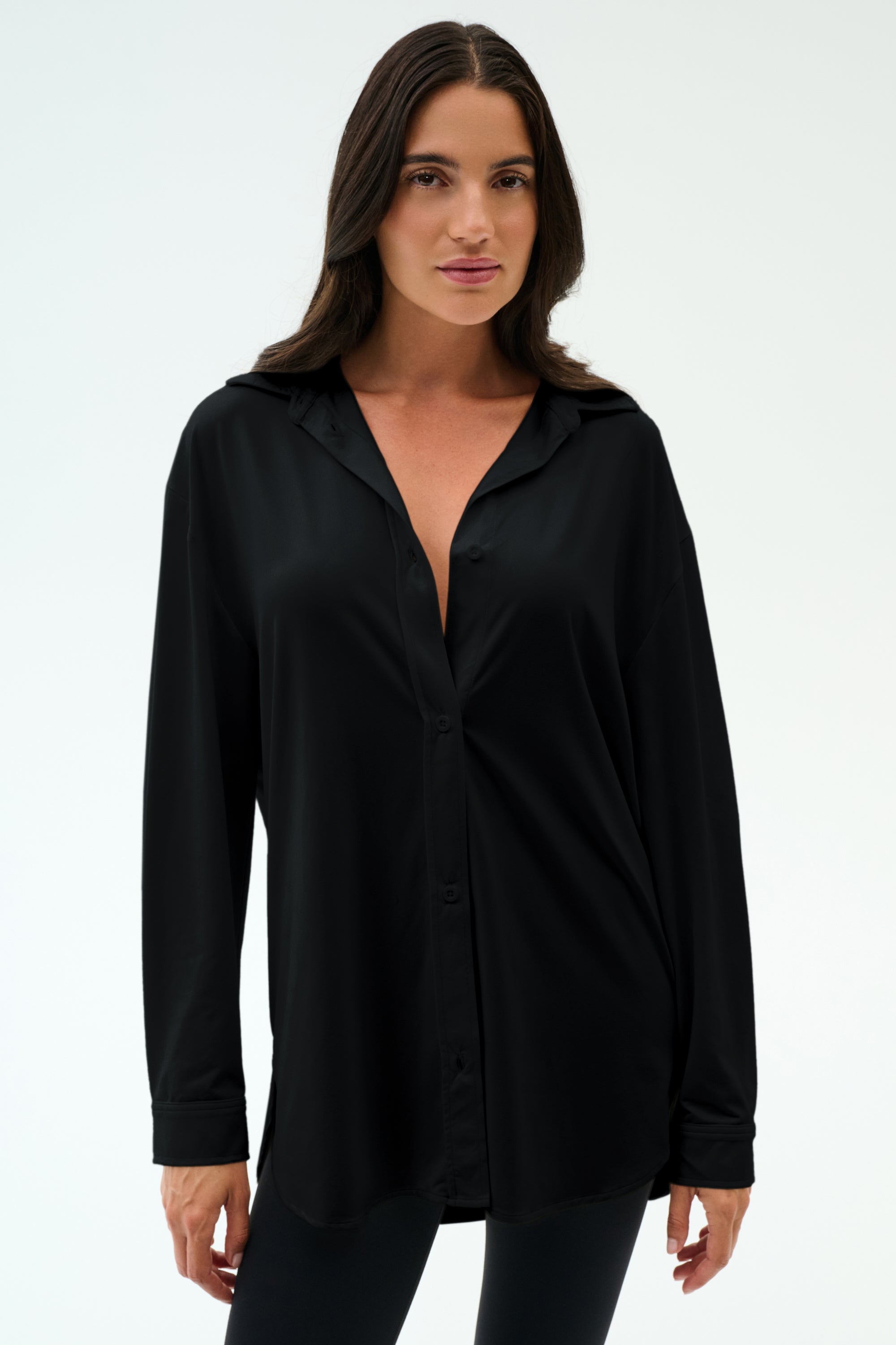 A woman with long dark hair wears the SPLITS59 Kate Airweight Lite Button Down and black pants, standing against a plain white background.