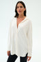 A woman wears the SPLITS59 Kate Airweight Lite Button Down in white with black pants against a light background—a versatile layering piece for any occasion.