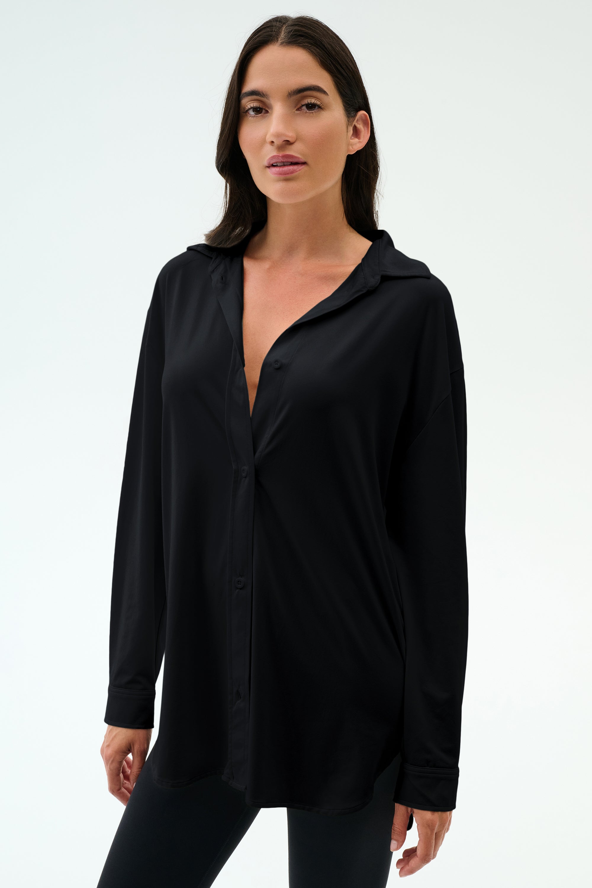 A woman with long dark hair models the SPLITS59 Kate Airweight Lite Button Down and black pants, standing against a plain white background.