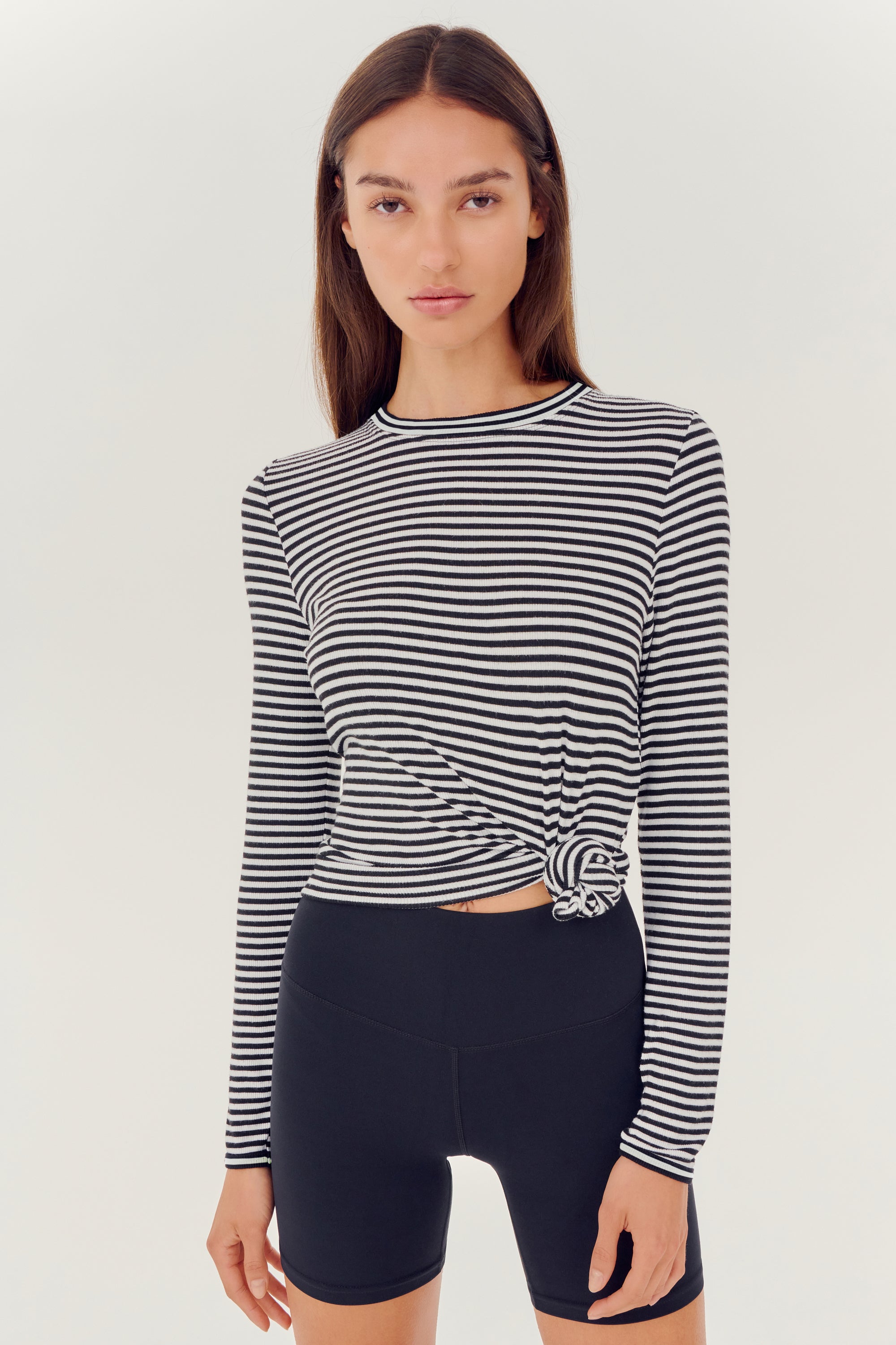 The model is wearing a SPLITS59 Louise Rib Long Sleeve - White/Black Stripe top designed for yoga.