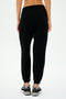 Back view of a person wearing SPLITS59's Andie Oversized Fleece Sweatpant in Black and black sneakers, ideal for cool weather workouts.