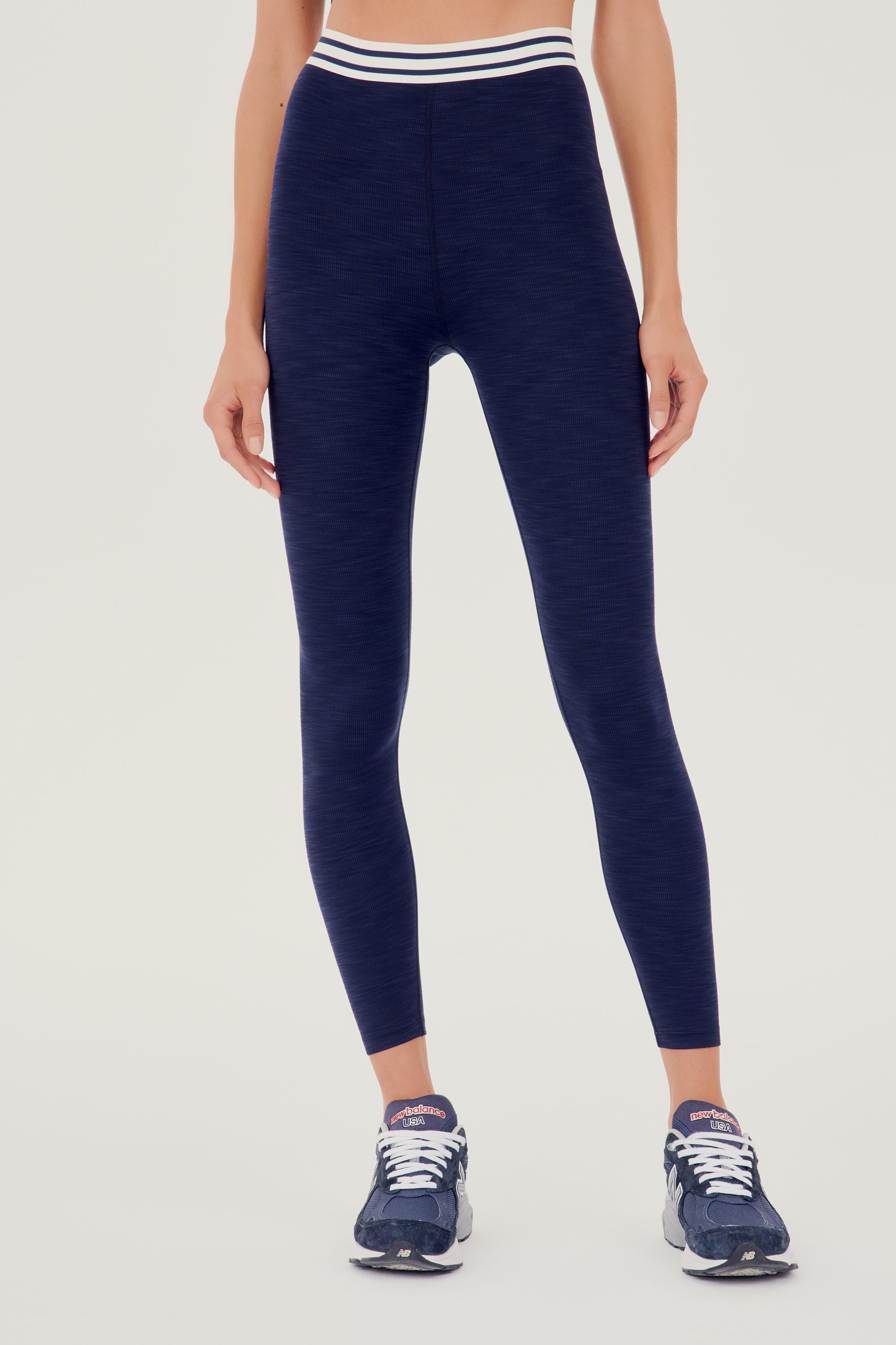 Front view of girl wearing a dark blue leggings with white and blue waistband  and dark blue shoes
