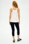 A person with long curly hair wears the Charlie Rib Tank in white by SPLITS59, paired with black leggings and sneakers, standing confidently against a white background.