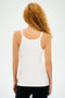 A person with long curly hair is seen from behind wearing the SPLITS59 Charlie Rib Tank in White and black pants, ready for gym workouts against a plain background.