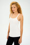 A person with curly hair is sporting the SPLITS59 Charlie Rib Tank in white along with black pants as they prepare for gym workouts, standing against a plain white background.