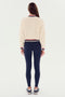 A woman stands facing away against a white background, wearing the SPLITS59 Willa Sherpa Jacket in cream, navy leggings, and gray sneakers.