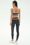A woman faces away, wearing SPLITS59's Mason High Waist Rigor Full Length leggings in Graphite/White with a matching sports bra and white sneakers, set against a plain light background.