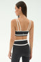 A woman faces away, wearing the SPLITS59 Eva Rigor Double Strap Bra in Graphite/White with matching high-waisted leggings—an ideal set for gym workouts.