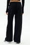 Shown from the back against a plain white background, a person wears SPLITS59 Brynn Airweight Pant in black with a black long-sleeve spandex top and white shoes.
