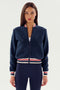 A person with long hair is wearing the Willa Sherpa Jacket - Indigo by SPLITS59, standing against a plain white background.