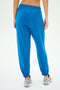 Wearing SPLITS59's Andie Oversized Fleece Sweatpant in Classic Blue and white sneakers, a person stands with their back to the camera against a plain background. Made in Los Angeles.