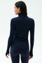 A woman faces away, wearing the SPLITS59 Lennon Rib Turtleneck in Indigo/White with matching leggings, set against a plain light background.