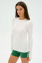 A person in a Louise Rib Long Sleeve by SPLITS59 and green shorts stands against a plain background, ready for gym workouts.