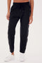 A person is wearing the Lucy Rigor Pant W/Piping - Black by SPLITS59, featuring relaxed fit and white side stripes, paired with white sneakers for all-day comfort.