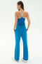 A woman stands with her back to the camera, wearing SPLITS59's Raven Fleece Full Length Sweatpant in Stone Blue and a matching blue racerback tank top, set against a plain light background.