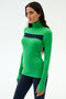 A woman stands against a white background in the SPLITS59 Lennon Rib Turtleneck - Grass/Indigo and navy leggings, ready for running or yoga.