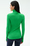 A woman with long dark hair, seen from behind, wears the SPLITS59 Lennon Rib Turtleneck in Grass/Indigo and dark leggings against a plain white background.
