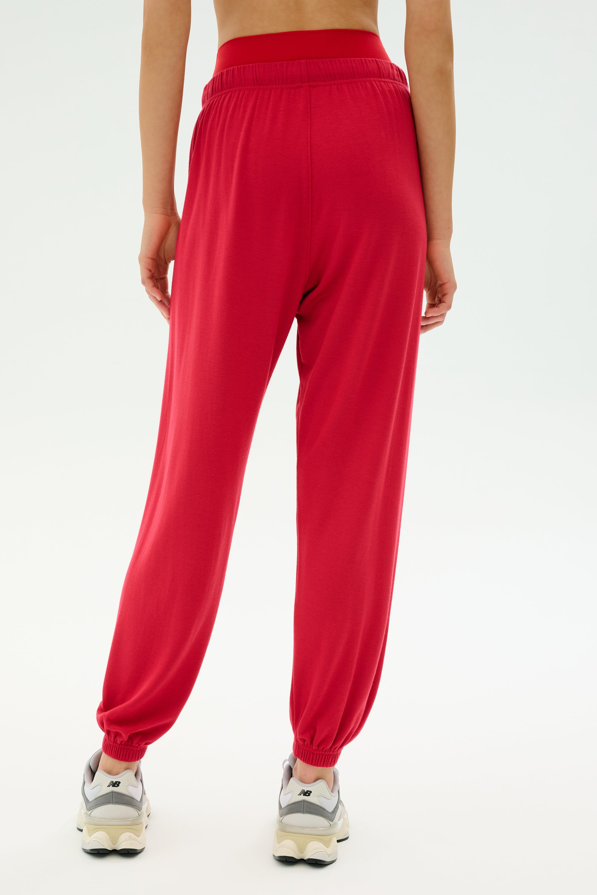 Model wears the SPLITS59 Andie Oversized Fleece Sweatpant in Pirate Red with white sneakers, captured from behind against a light background—ideal for stylish, cool weather workouts.