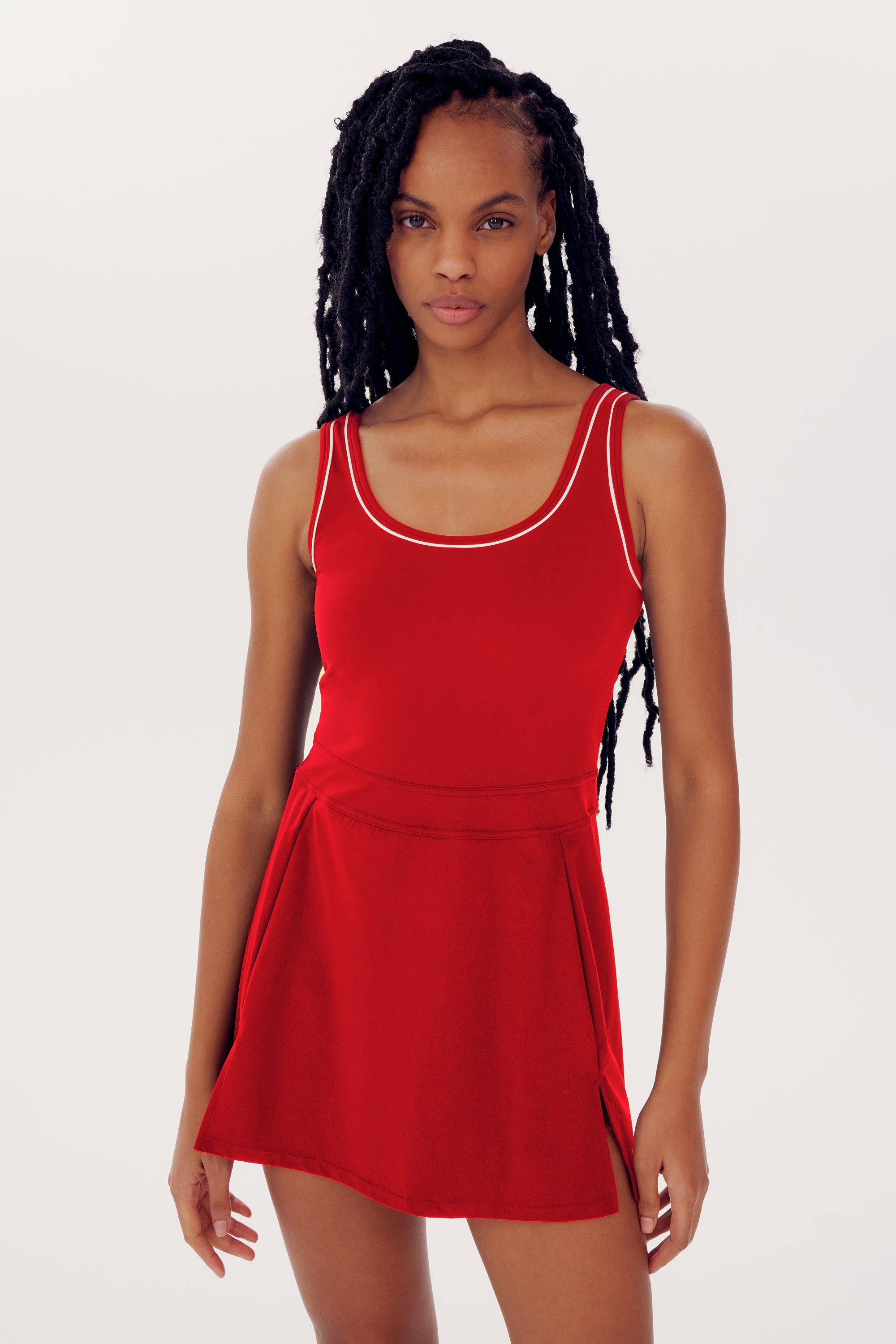 Person with long braided hair wearing a vibrant red SPLITS59 Martina Rigor Dress w/Piping - Pirate Red, standing against a plain white background.