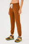 Full front view of woman wearing dark orange sweatpant jogger with white drawstring  paired with dark green, orange and light green shoes