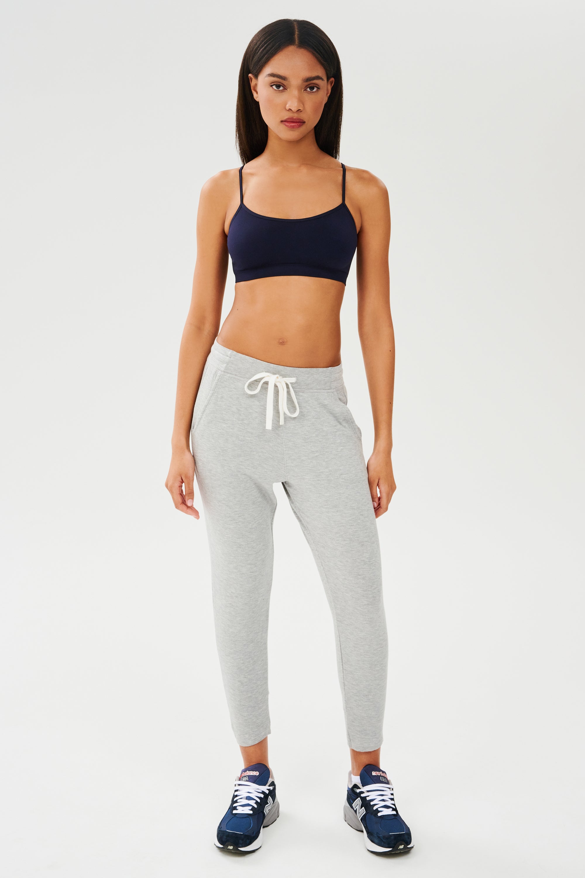 A woman wearing a SPLITS59 Loren Seamless Bra in Indigo and sweatpants.