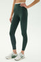 Someone wearing SPLITS59 Dual High Waist Airweight 7/8 leggings in Military/White stands against a plain light background with white athletic shoes.