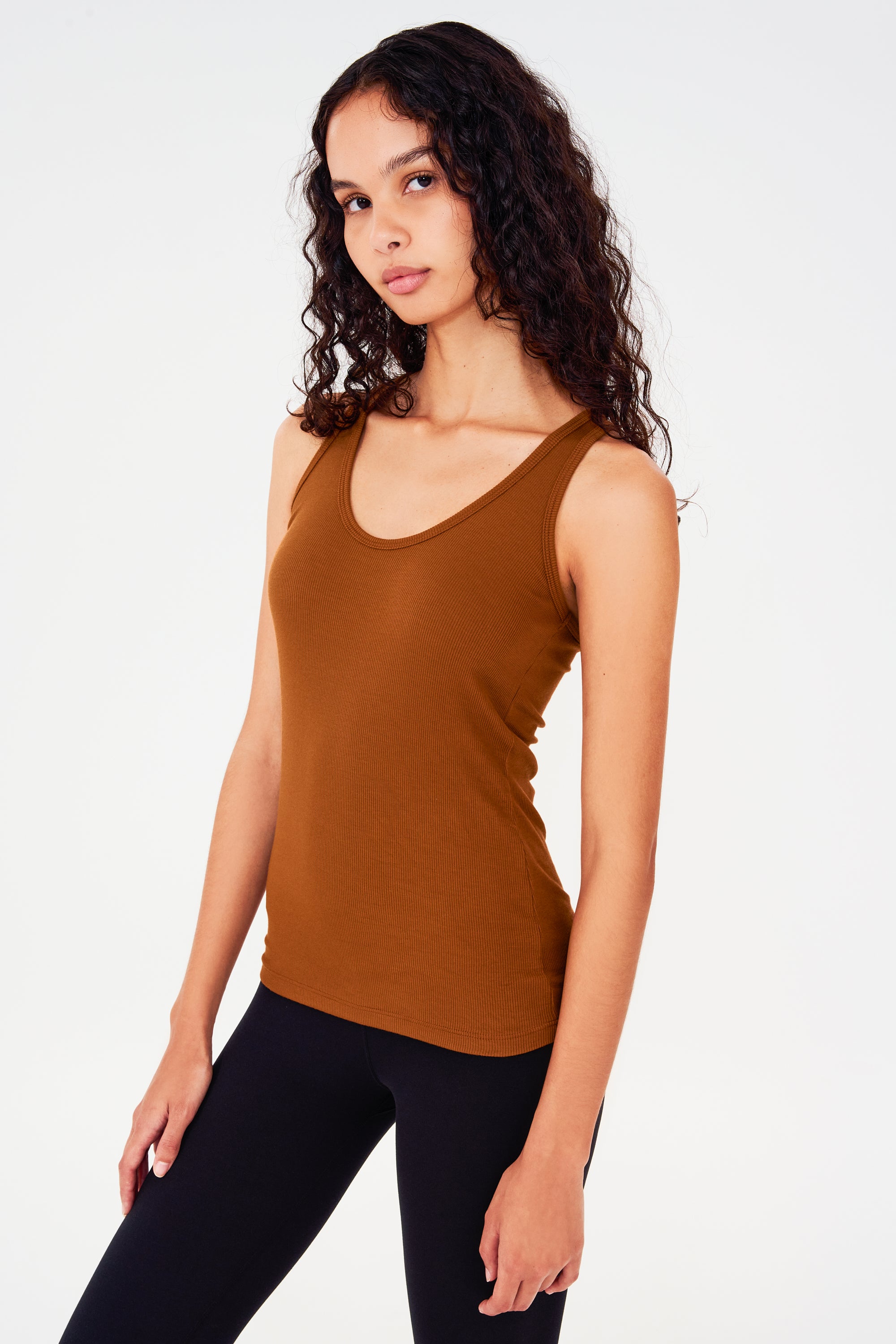 Side view of girl wearing a reddish brown tank top and black leggings
