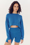 Woman in a SPLITS59 Noah Fleece Crop Sweatshirt - Stone Blue and matching shorts, both made from a modal spandex blend.