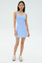 A woman faces forward against a plain white background, wearing the SPLITS59 Martina Rigor Dress in Skylight and silver athletic shoes—an ideal look for high-impact workouts.