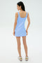 A woman faces away, wearing the SPLITS59 Martina Rigor Dress in Skylight with sneakers against a plain, light background, channeling classic court sports style.