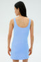 A woman with long dark hair wears the SPLITS59 Martina Rigor Dress in Skylight, standing and facing away from the camera against a plain light background.