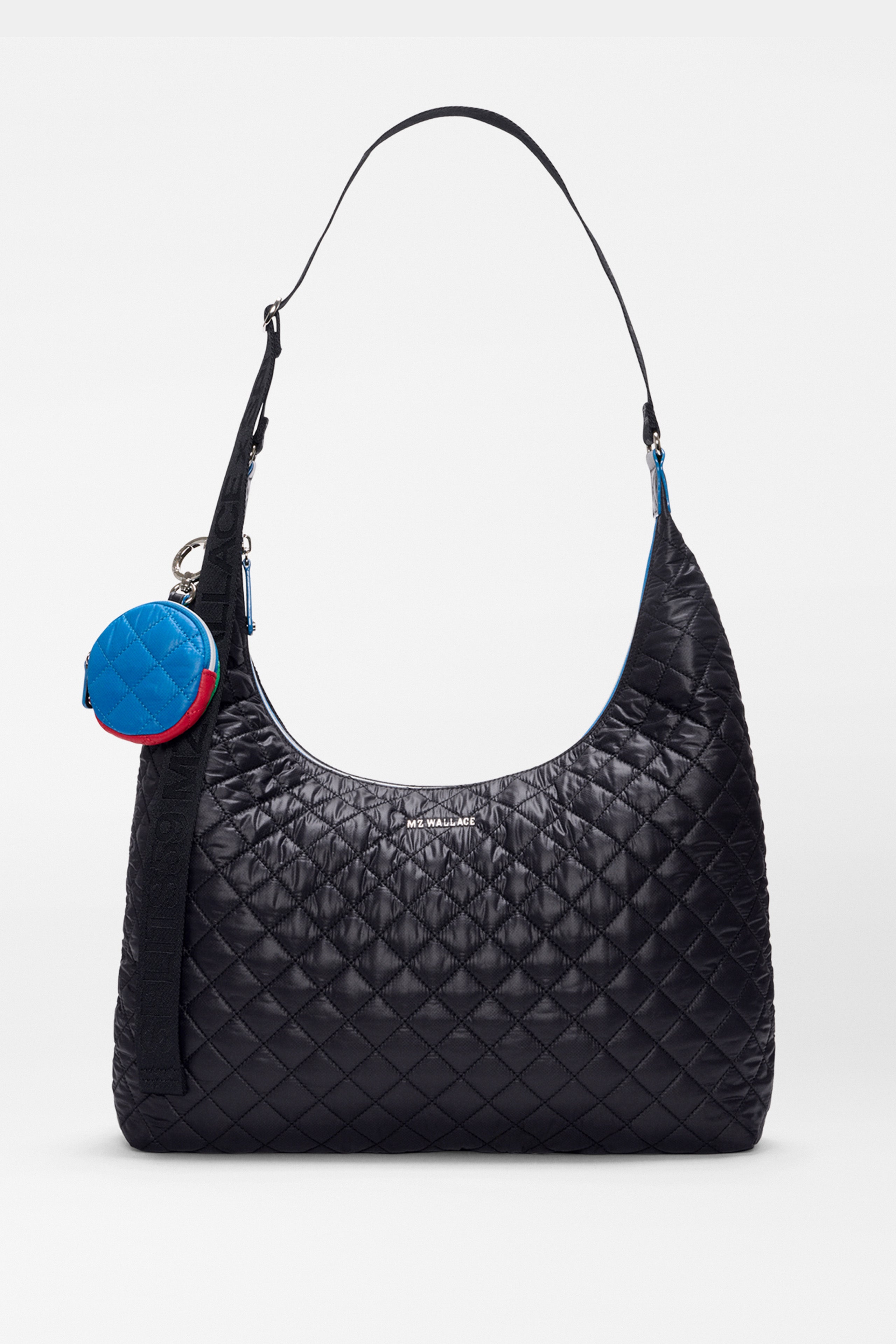 The SPLITS59 MZW x Splits59 Carry All is a black quilted shoulder bag featuring a curved strap and a small, round blue-and-red coin pouch attached to the handle.