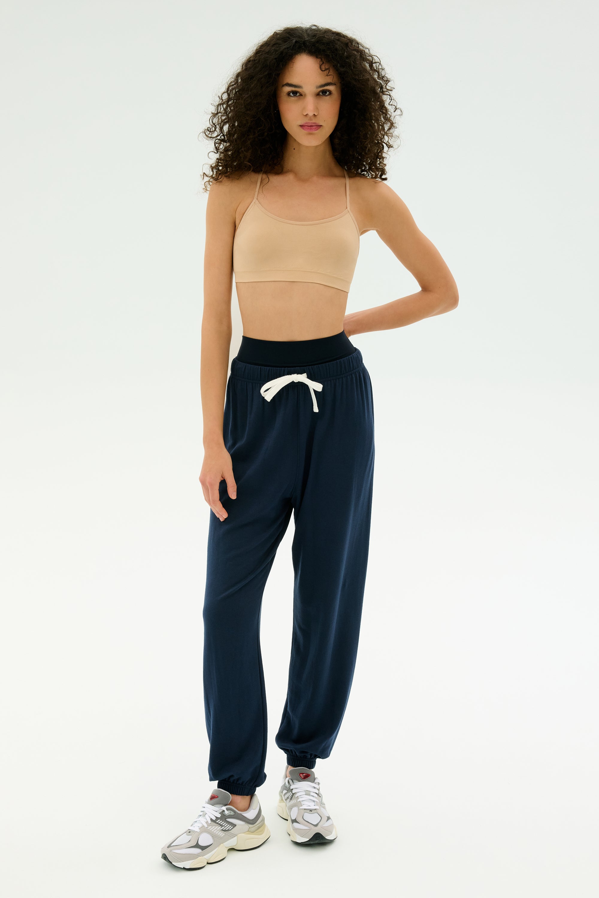 A woman stands against a plain background wearing the SPLITS59 Andie Oversized Fleece Sweatpant in Indigo—perfect for cool weather workouts. MADE IN LOS ANGELES.