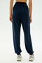 Person wearing SPLITS59 Andie Oversized Fleece Sweatpant in Indigo and white sneakers, shown from the back against a plain light background—perfect for cool weather workouts. MADE IN LOS ANGELES.