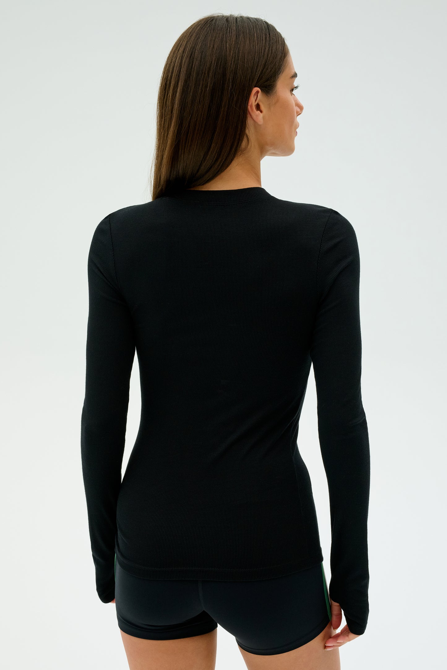 Individual wearing a black Louise Rib Long Sleeve from SPLITS59 and shorts, facing away against a plain background. Crafted in Los Angeles.