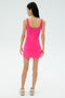 A person stands against a light background, facing away from the camera, wearing the SPLITS59 Martina Rigor Dress in Berry with sneakers.
