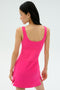 A woman faces away in the SPLITS59 Martina Rigor Dress - Berry, a sleeveless bright pink style with side slits, set against a plain light background.