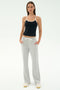 A woman faces forward in a black tank top with white trim, SPLITS59 Raven Fleece Full Length Sweatpant in Heather Grey, and white sneakers, standing against a plain background.